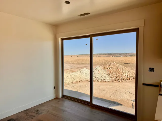 Sliding glass door leading to an outdoor area, wood-finish flooring, recessed lighting, and a white trim package