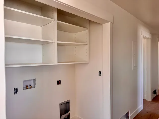 Built-in shelving with adjustable shelves, white wall finishes, and wood-finish flooring