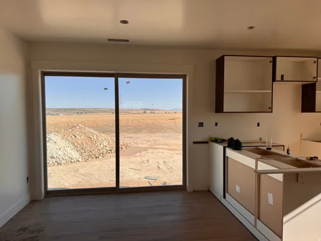 Wood-finish flooring, recessed ceiling lighting, sliding glass door, under-construction cabinetry, and partial upper cabinetry