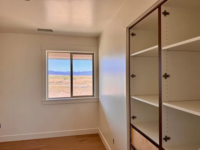 Wood-finish flooring, built-in shelving, built-in drawers, and a window with white trim