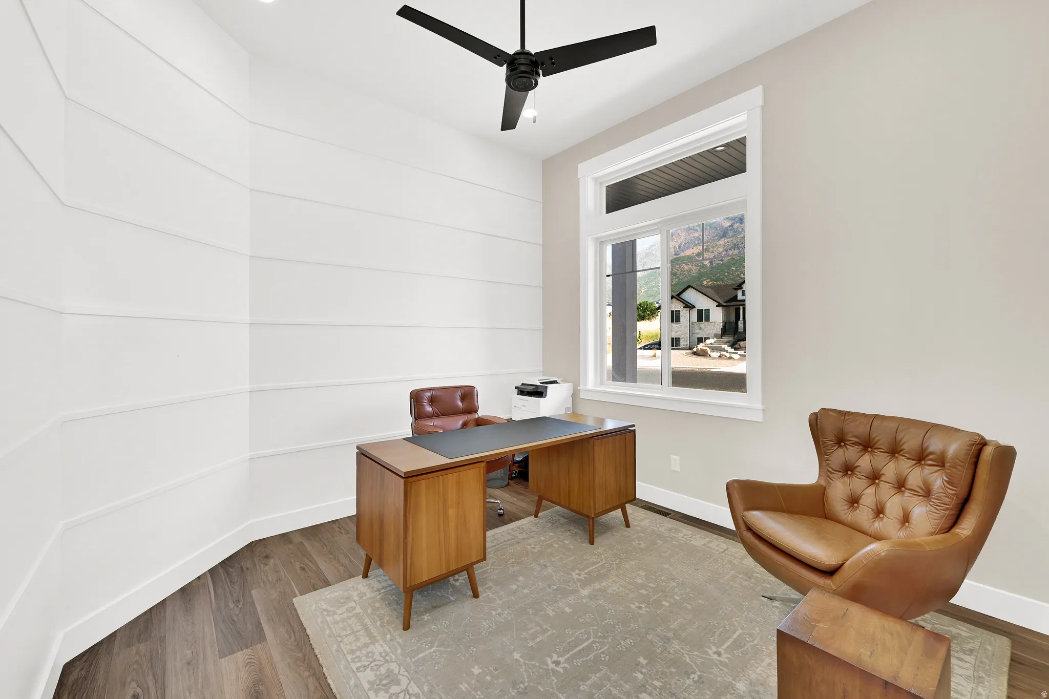 Interior room featuring horizontal wall paneling, a large window with white trim, and wood-finish flooring