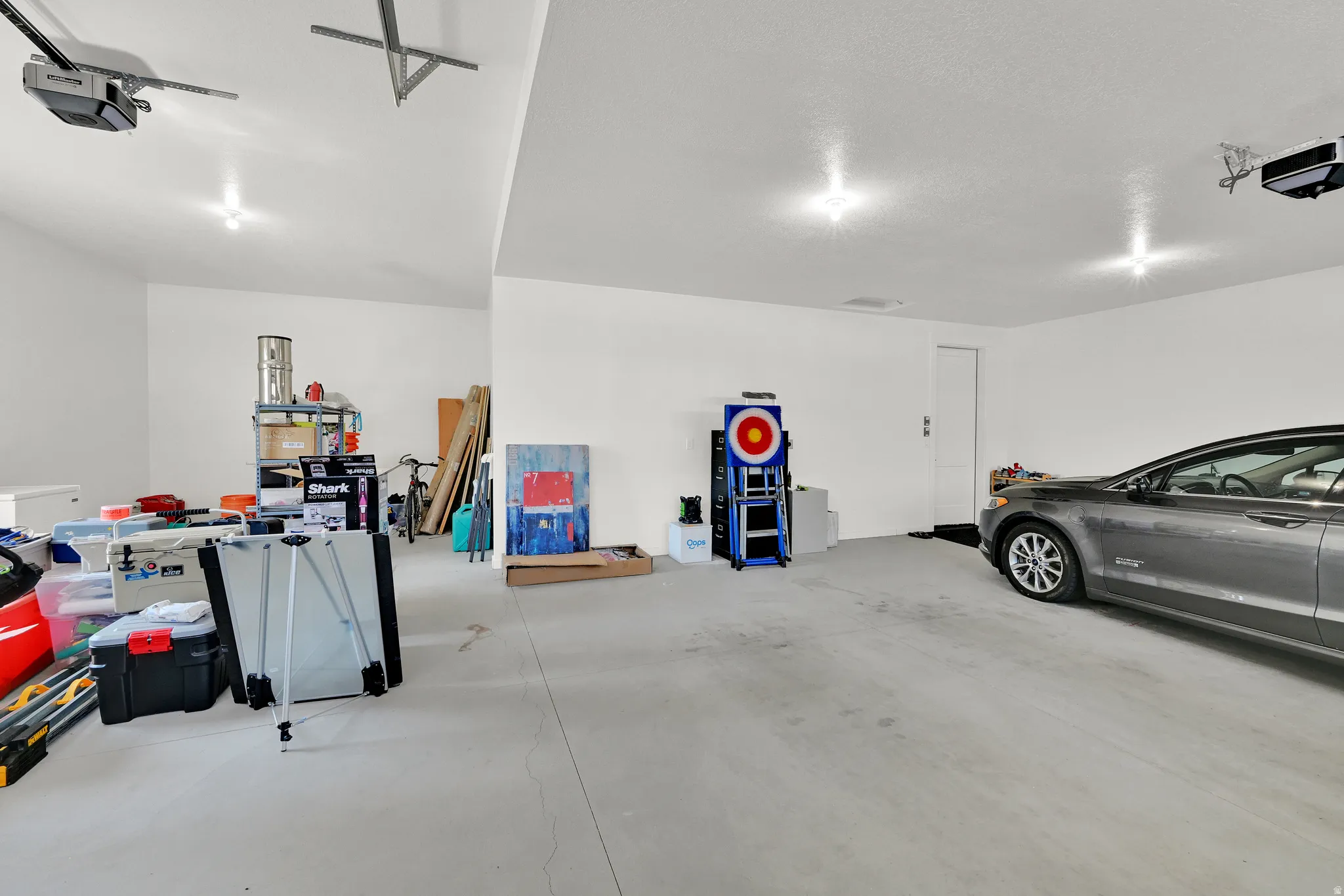 Spacious garage featuring a concrete floor, bright overhead lighting, and two automatic garage door openers