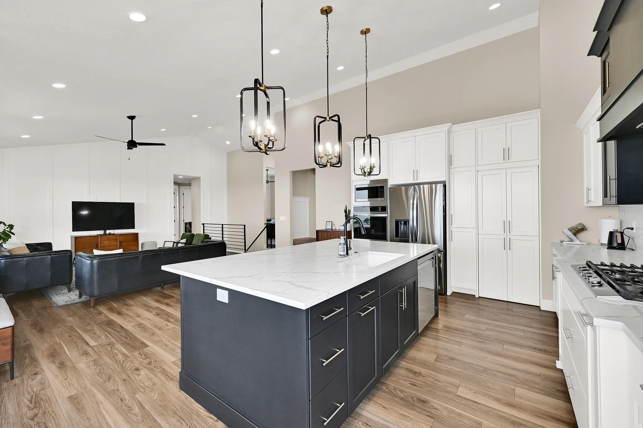 Kitchen island featuring a white quartz countertop, integrated sink, and dark cabinetry