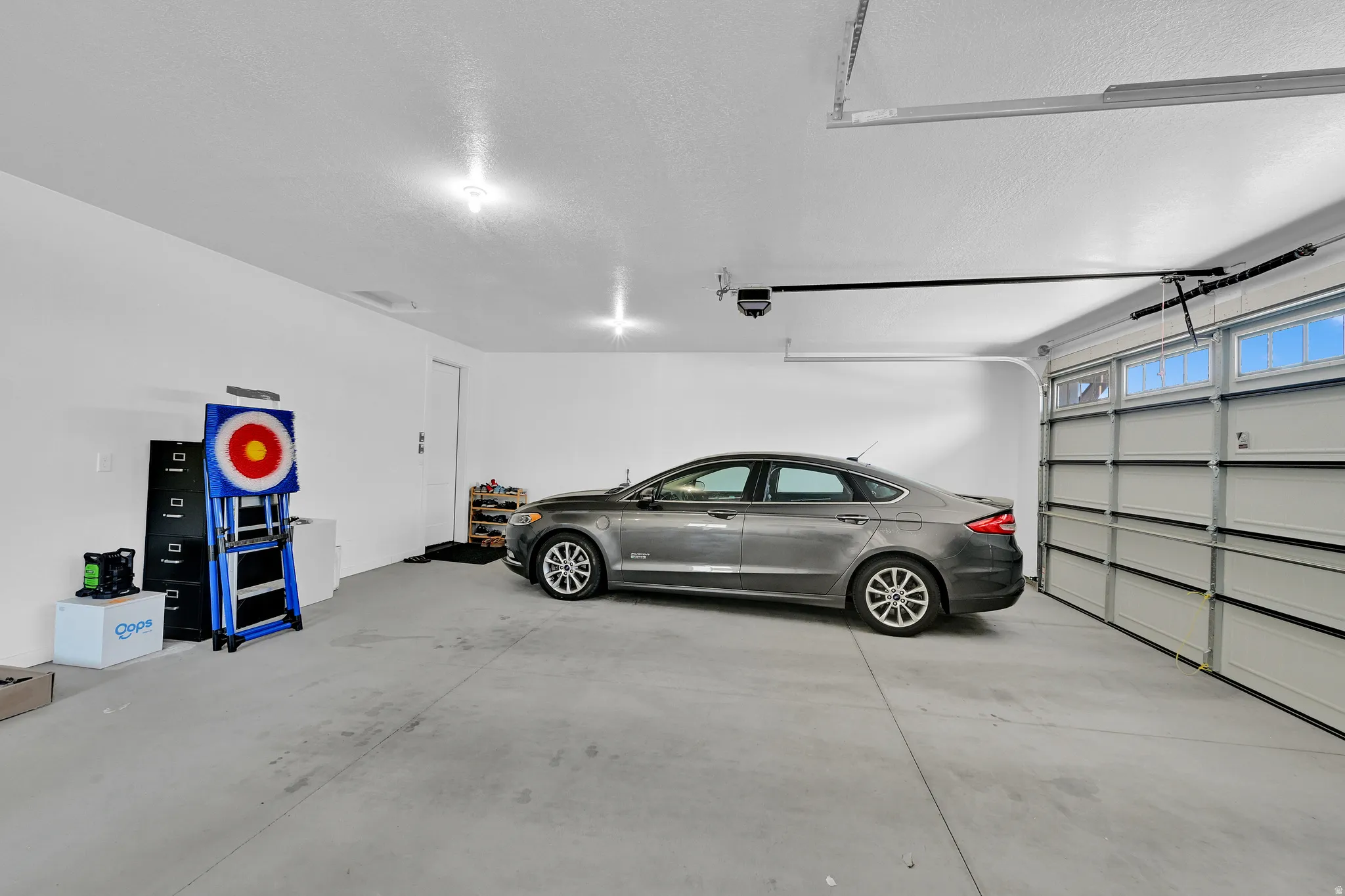 Spacious garage featuring a concrete floor, bright overhead lighting, and a two-car capacity