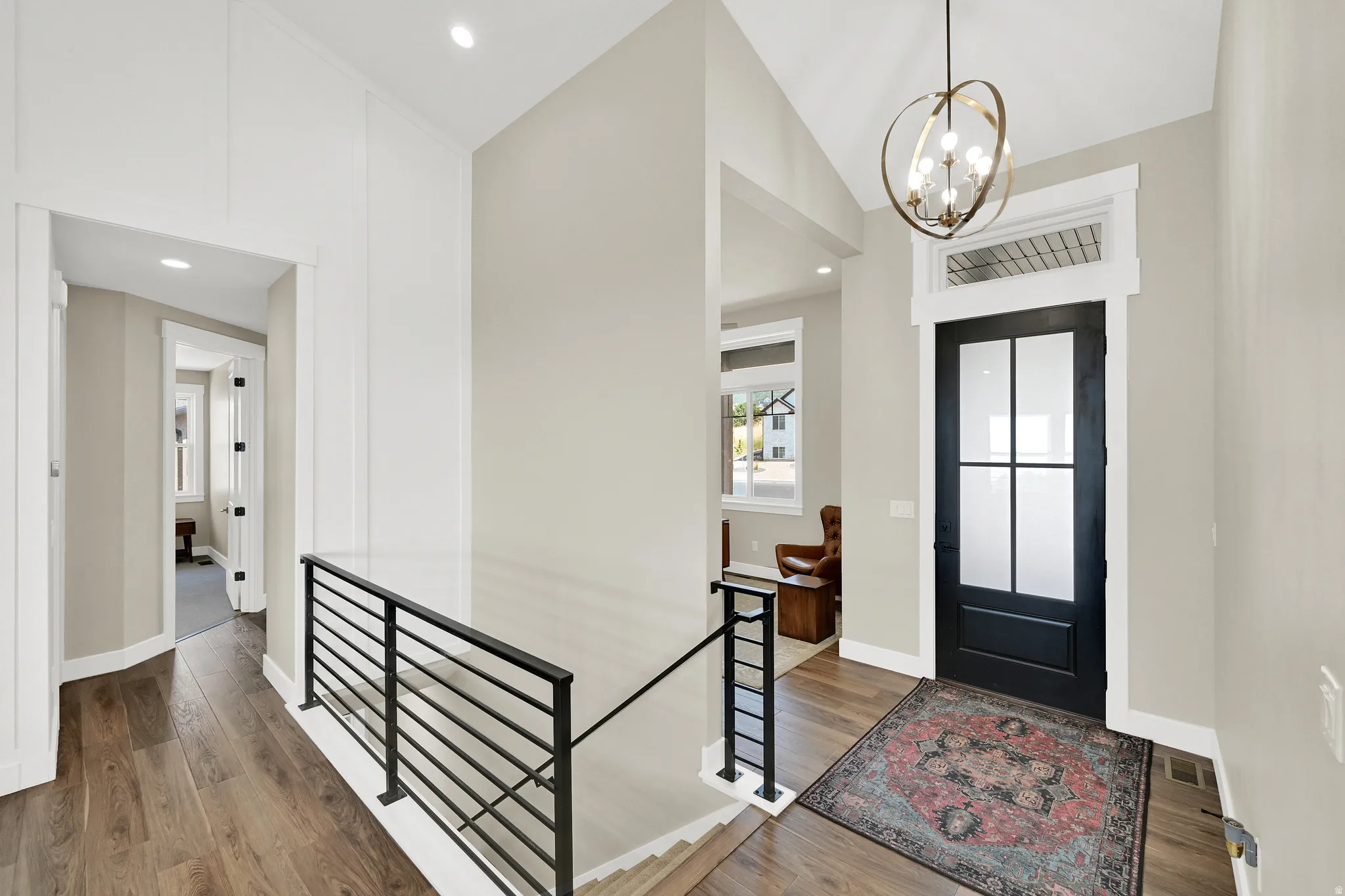 Entryway featuring a black paneled door with frosted glass inserts, a decorative chandelier, and wood-finish flooring