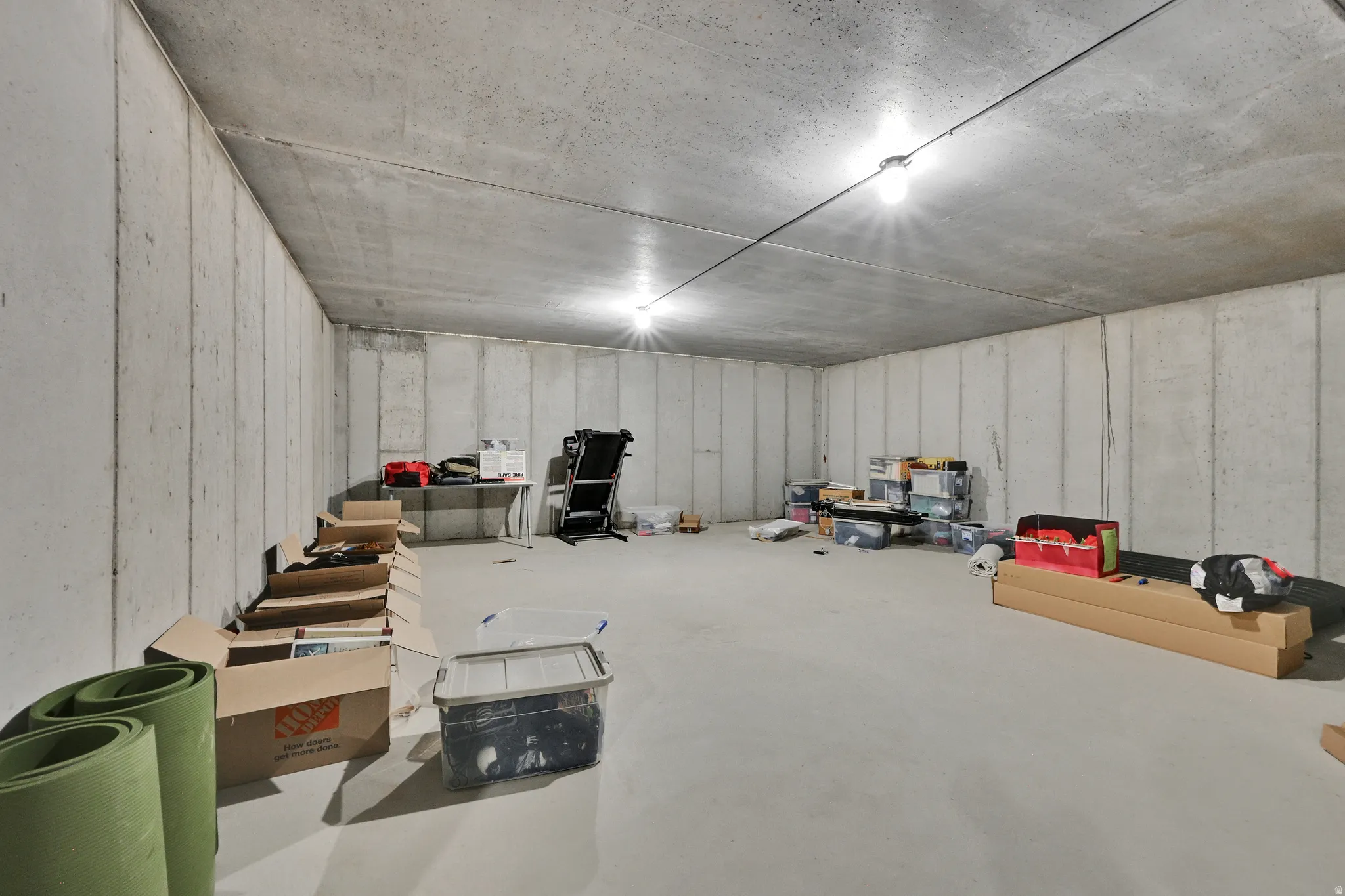 Spacious unfinished basement featuring concrete walls and flooring, with visible overhead lighting