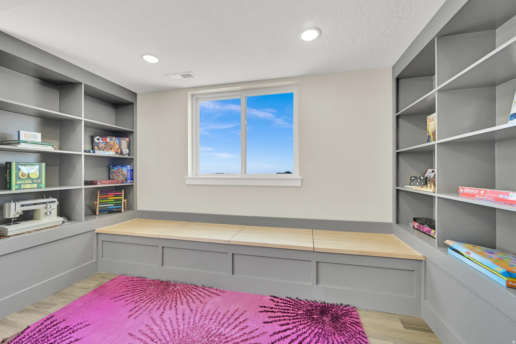 Built-in shelving units flank a window seat with natural wood tops