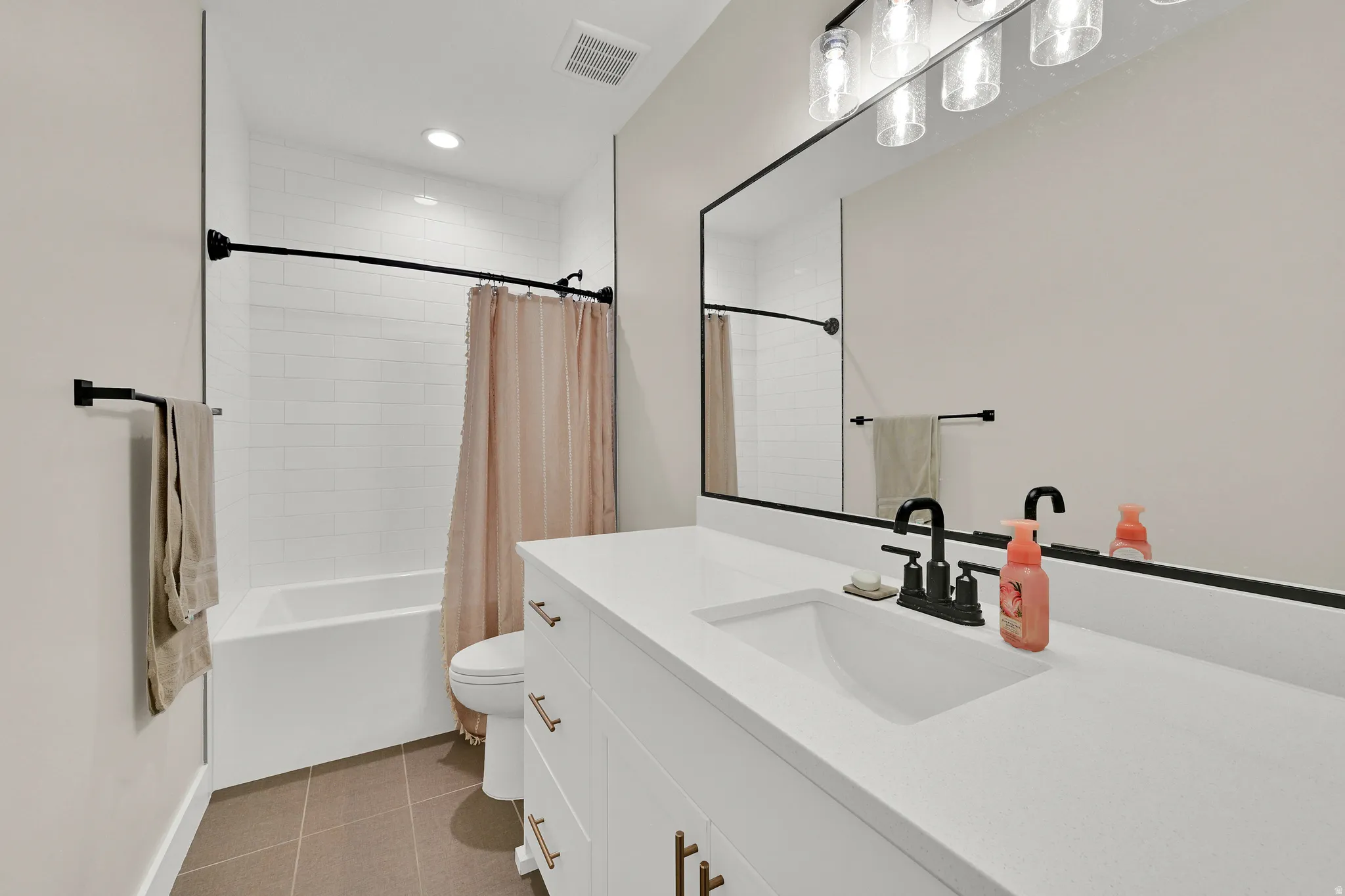 Bathroom featuring a white subway tile shower surround, a built-in tub, and matte black fixtures