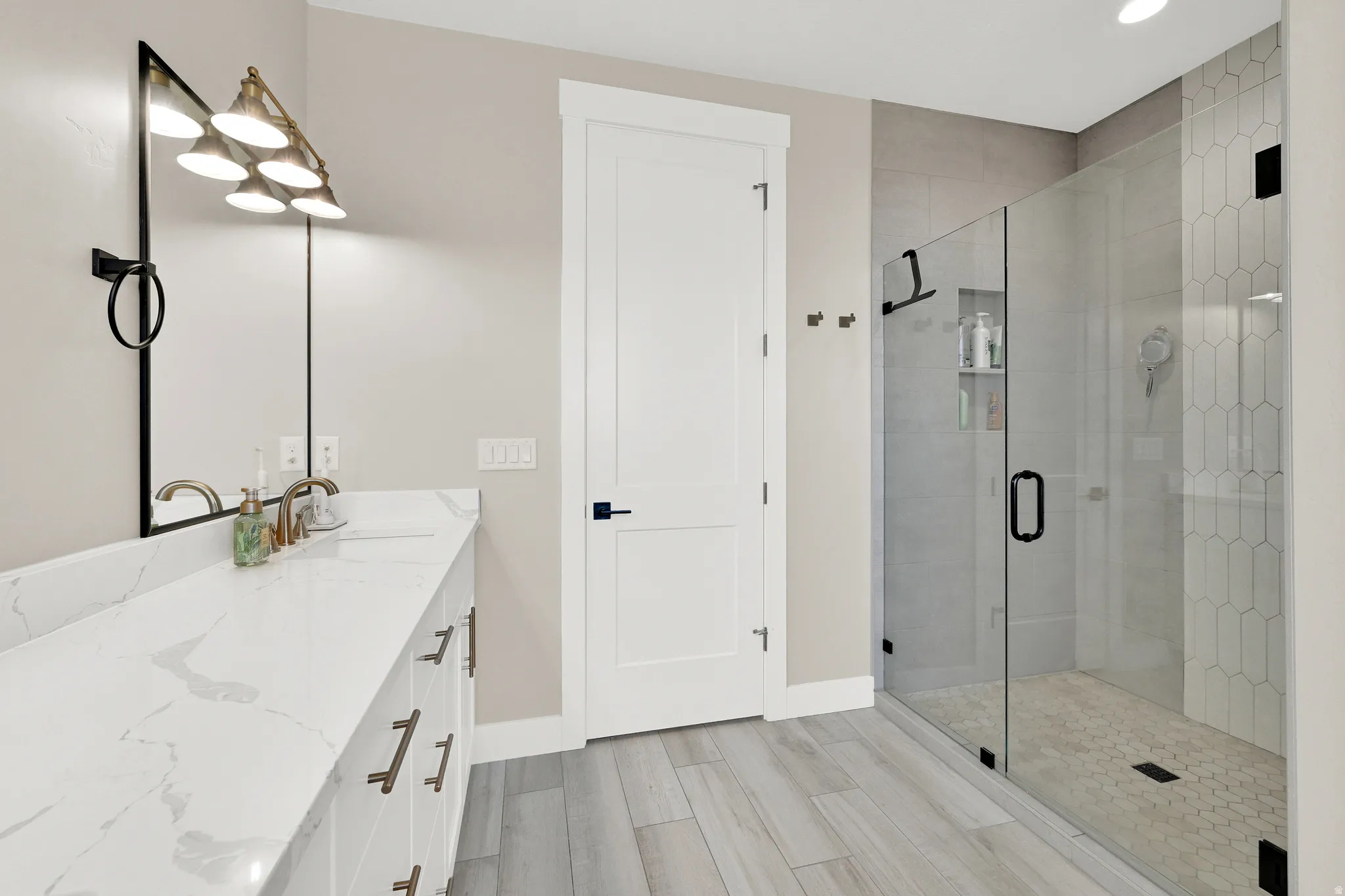 Bathroom featuring an extended double vanity with integrated sinks and a glass-enclosed shower