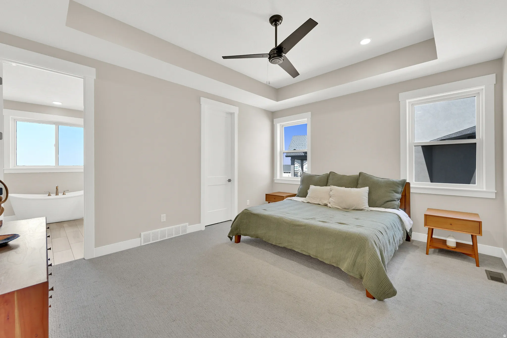Spacious bedroom featuring a tray ceiling, recessed lighting, and a modern ceiling fan