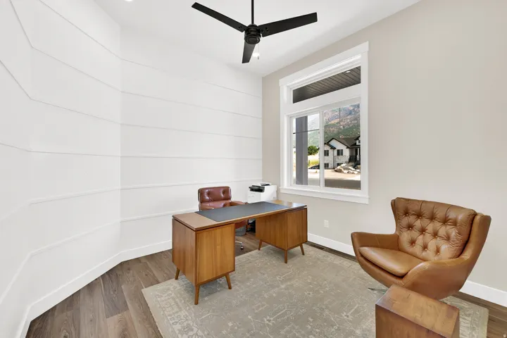 Interior room featuring horizontal wall paneling, a large window with white trim, and wood-finish flooring