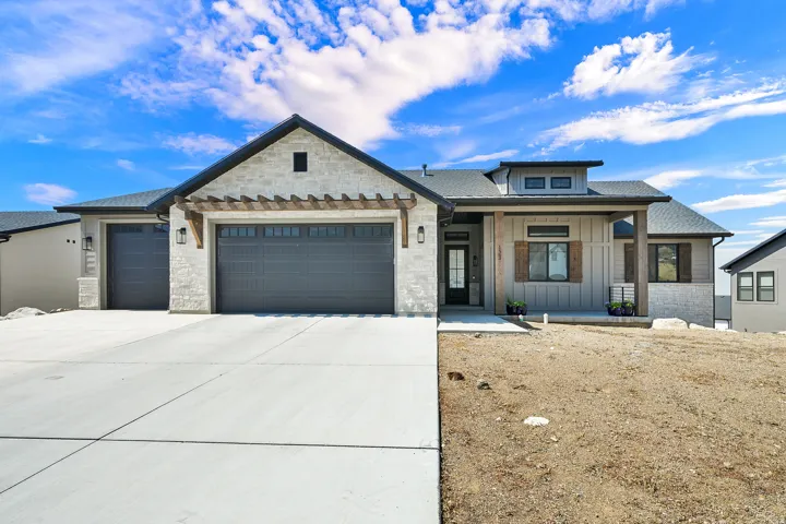 Contemporary ranch-style exterior featuring stone and vertical siding accents, a prominent front porch with wood-finish columns, a two-car garage with pergola detailing, and an additional single-car garage