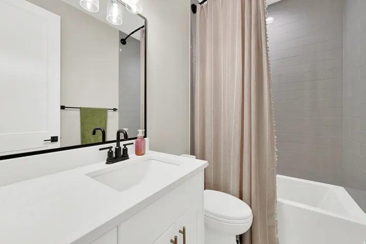 Bathroom featuring a white vanity with a rectangular sink, matte black faucet, and a large framed mirror