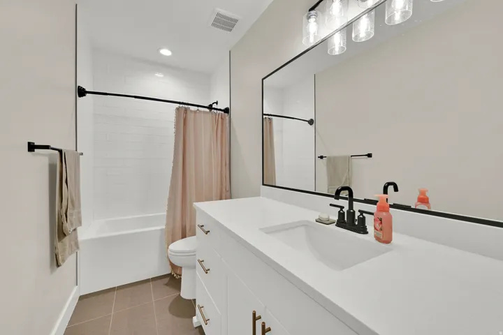 Bathroom featuring a white subway tile shower surround, a built-in tub, and matte black fixtures