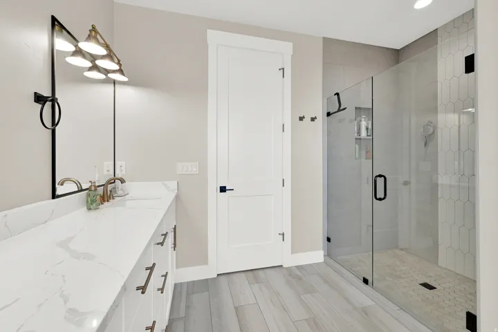 Bathroom featuring an extended double vanity with integrated sinks and a glass-enclosed shower