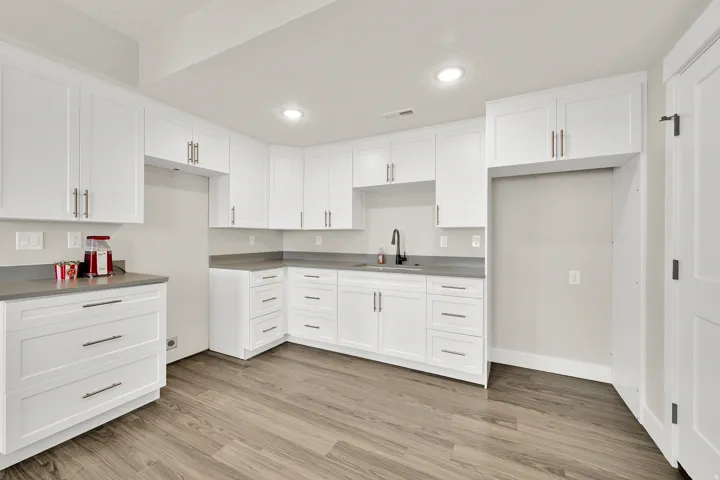 Kitchenette featuring white shaker-style cabinetry, dark wood-finish flooring, gray countertops, and a matte black gooseneck faucet