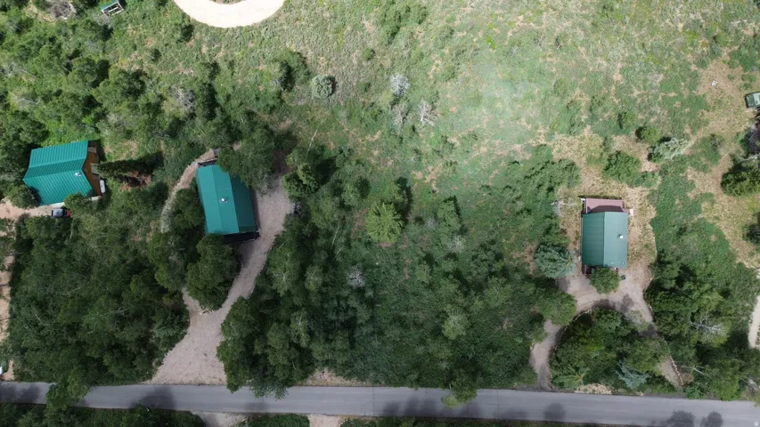Aerial property overview featuring three structures with green roofs, surrounded by dense natural landscaping