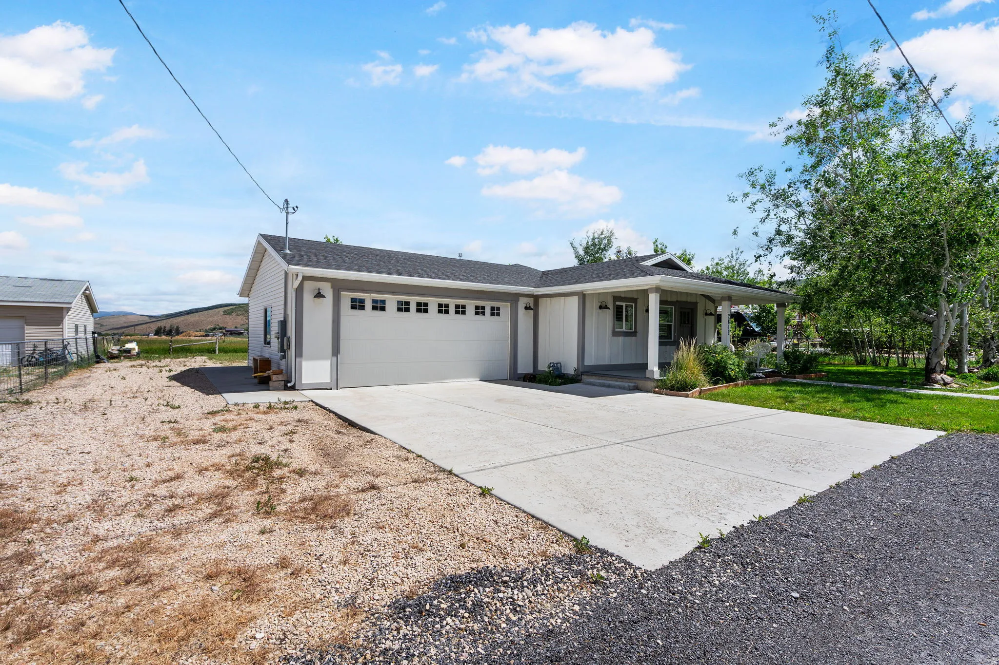 Contemporary ranch-style home featuring a covered front porch, an attached two-car garage with transom windows, and a paved driveway