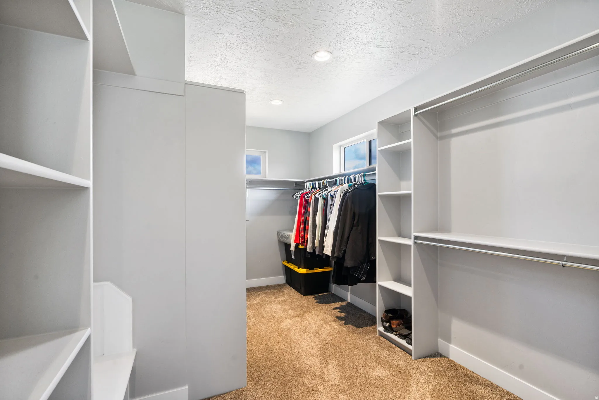 Spacious walk-in closet featuring built-in shelving, hanging rods, and recessed lighting