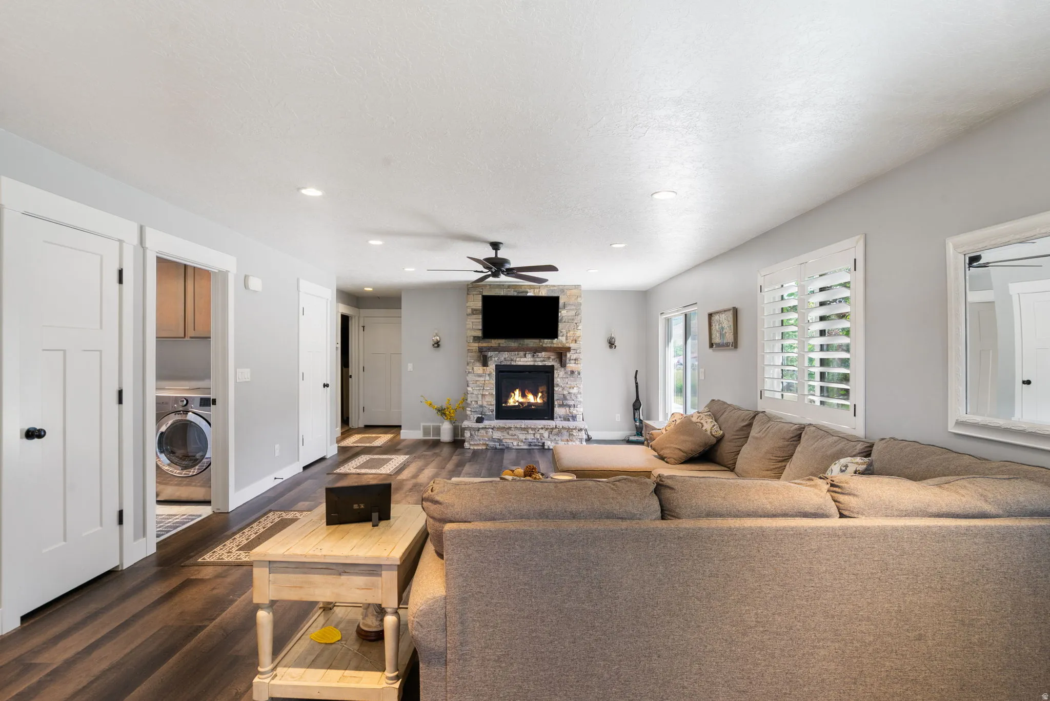 Living area featuring a stone-clad fireplace, wood-finish flooring, recessed lighting, and a ceiling fan