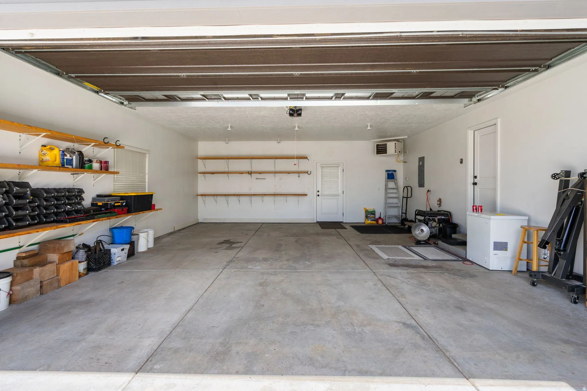 Spacious garage featuring a concrete floor, white painted walls, and an overhead garage door