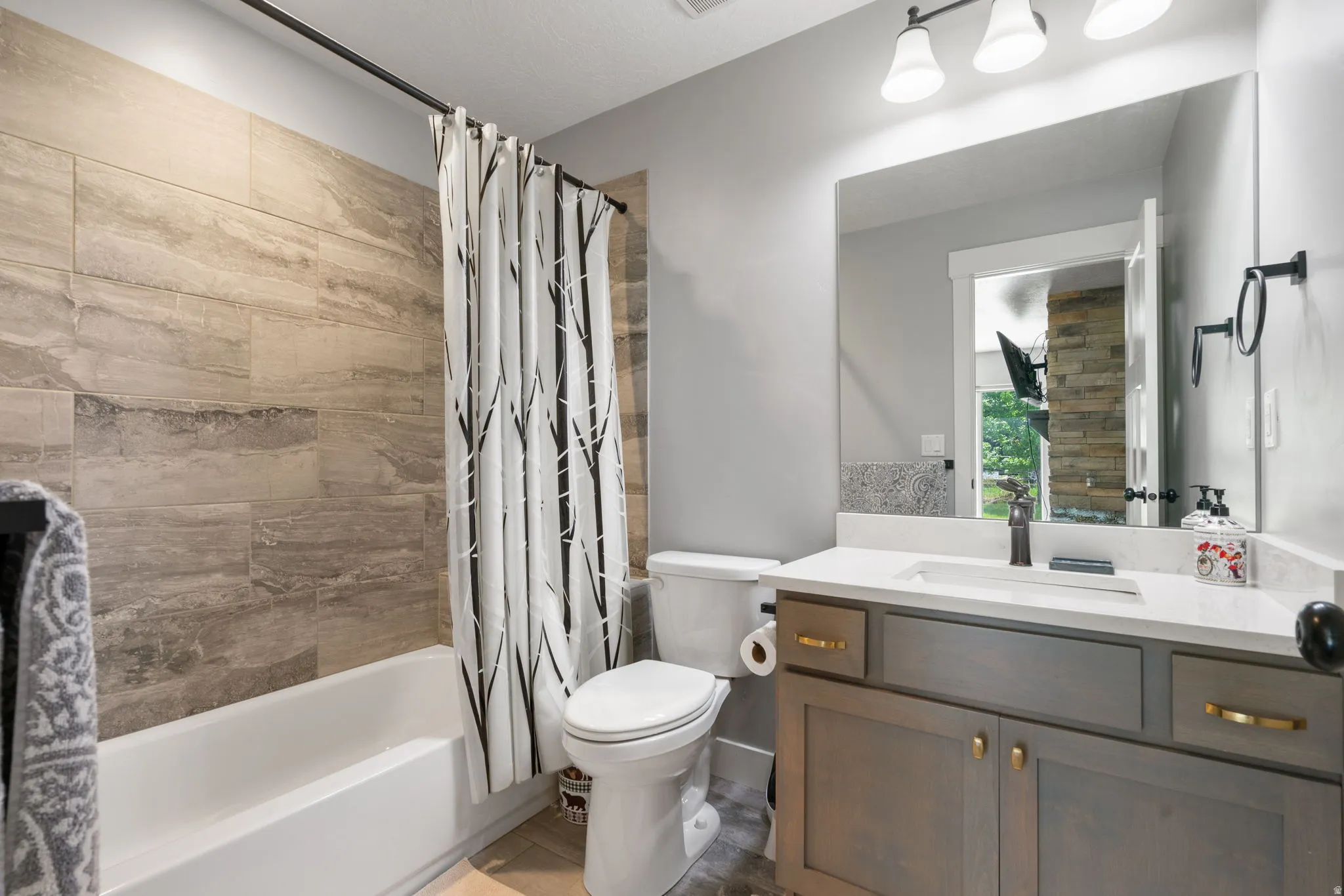 Bathroom featuring a white tub with floor-to-ceiling textured tile surround