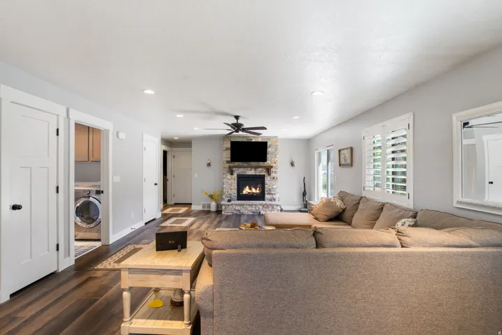 Living area featuring a stone-clad fireplace, wood-finish flooring, recessed lighting, and a ceiling fan