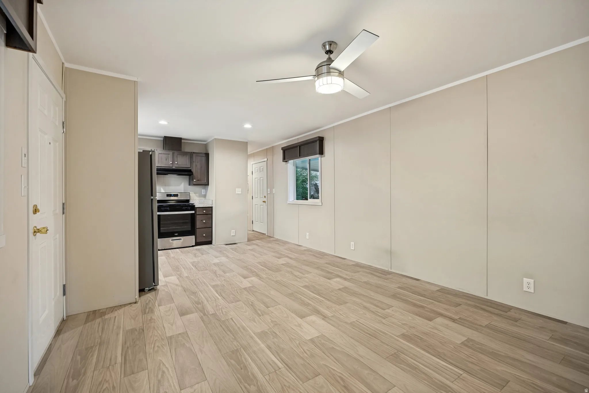 Open concept living area featuring wood-finish flooring, a ceiling fan with integrated lighting, and recessed ceiling lighting
