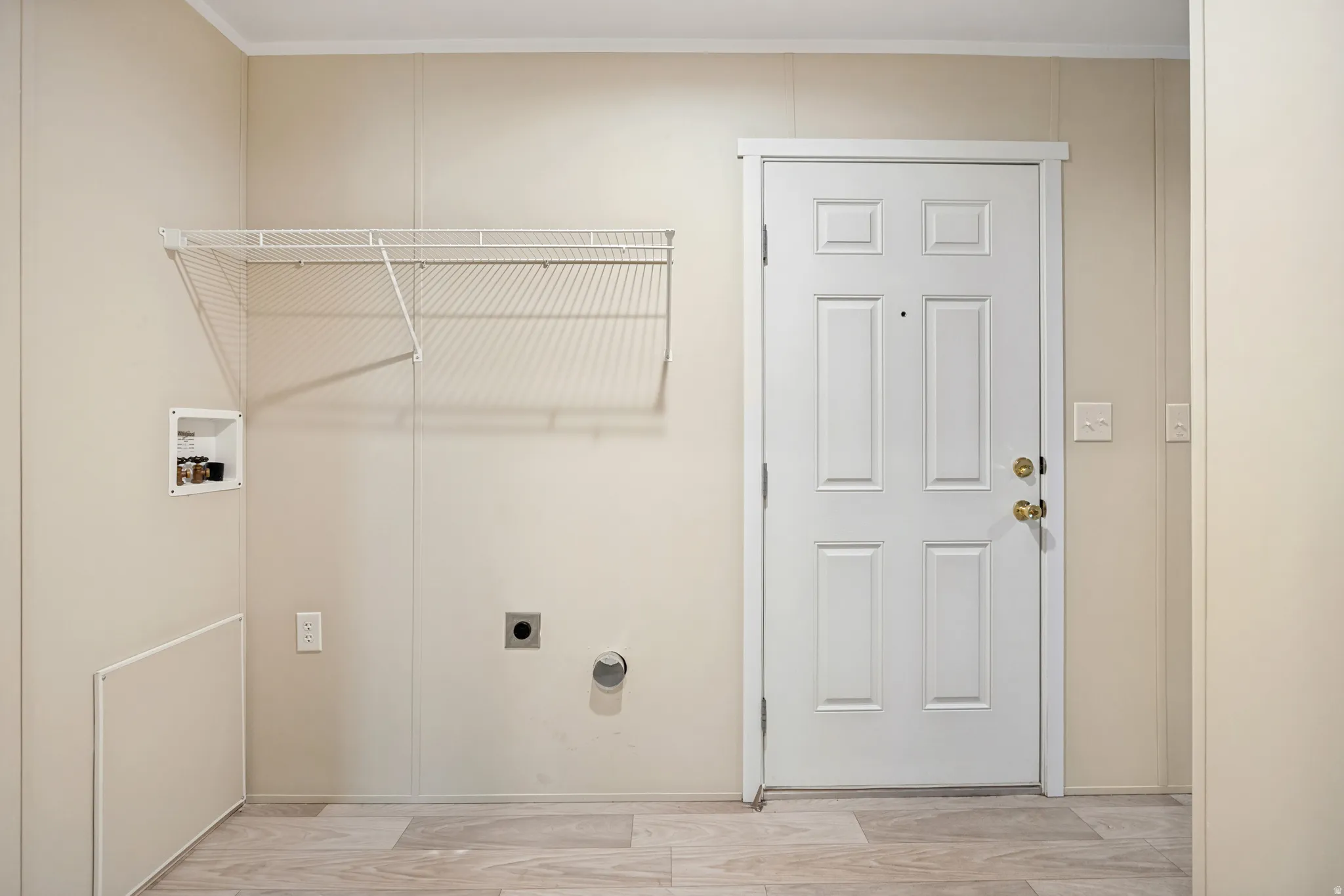 Utility area featuring pale wall paneling and light wood-finish flooring