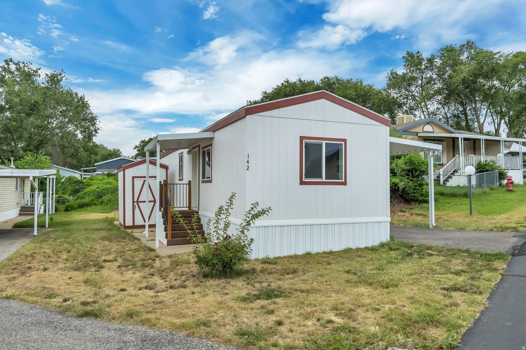 White siding exterior with a contrasting red trim roofline and white window frames