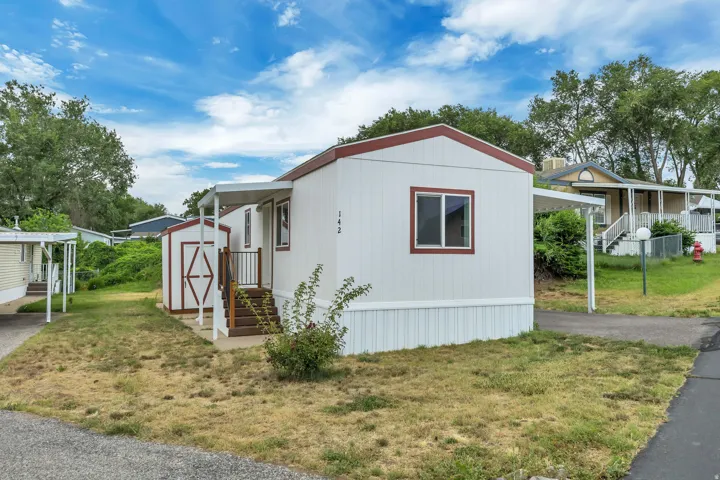 White siding exterior with a contrasting red trim roofline and white window frames