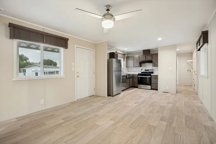 Open-concept living area featuring light wood-finish flooring, a contemporary ceiling fan with integrated lighting, and recessed ceiling lights