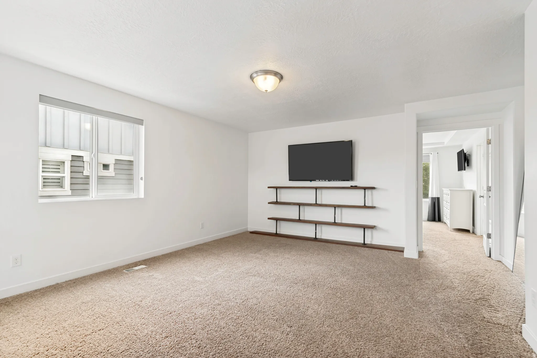 Spacious room featuring neutral carpeting and white wall finishes