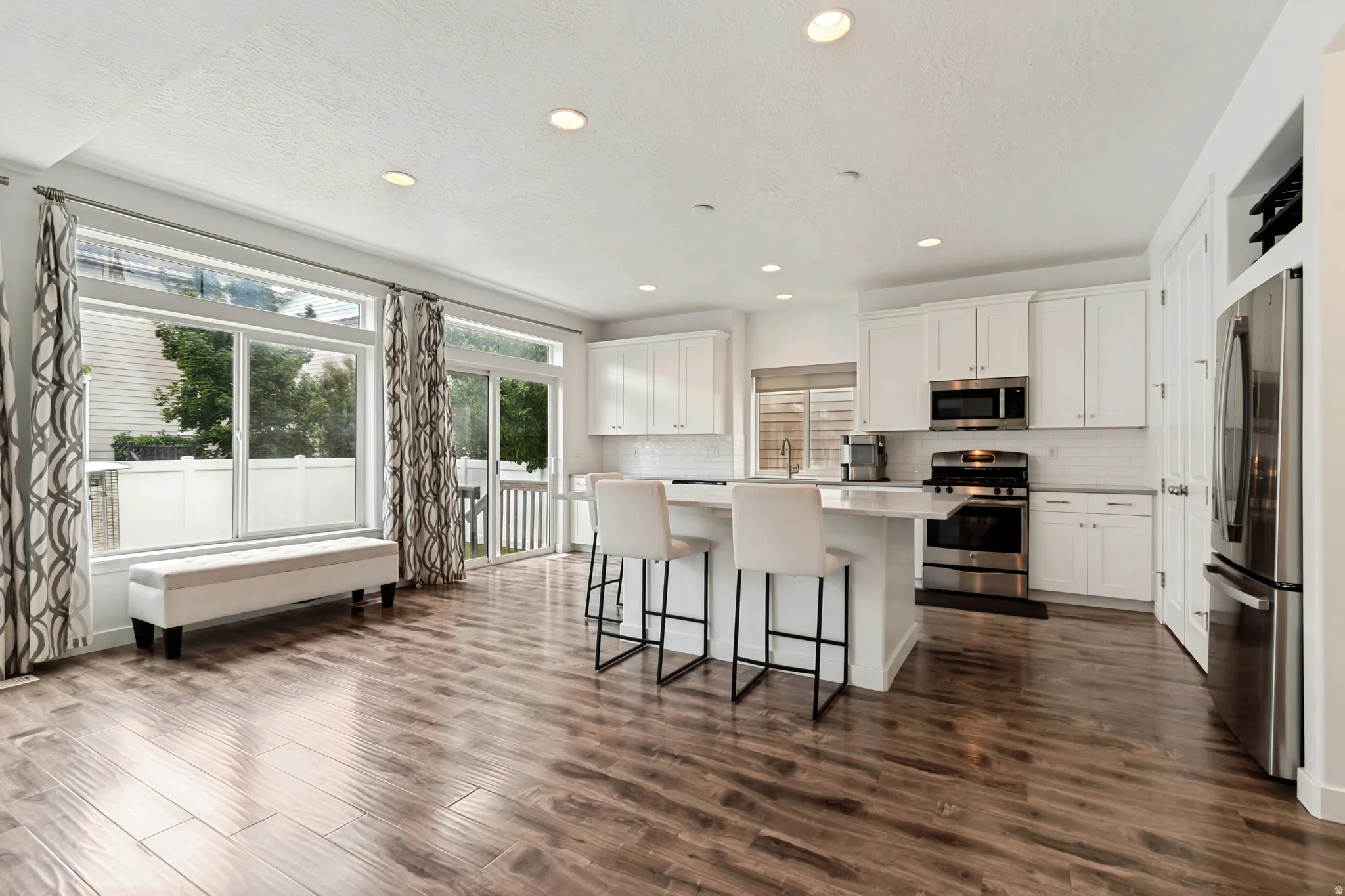 Open-concept kitchen and living area featuring wood-finish flooring, recessed lighting, and a kitchen island with seating