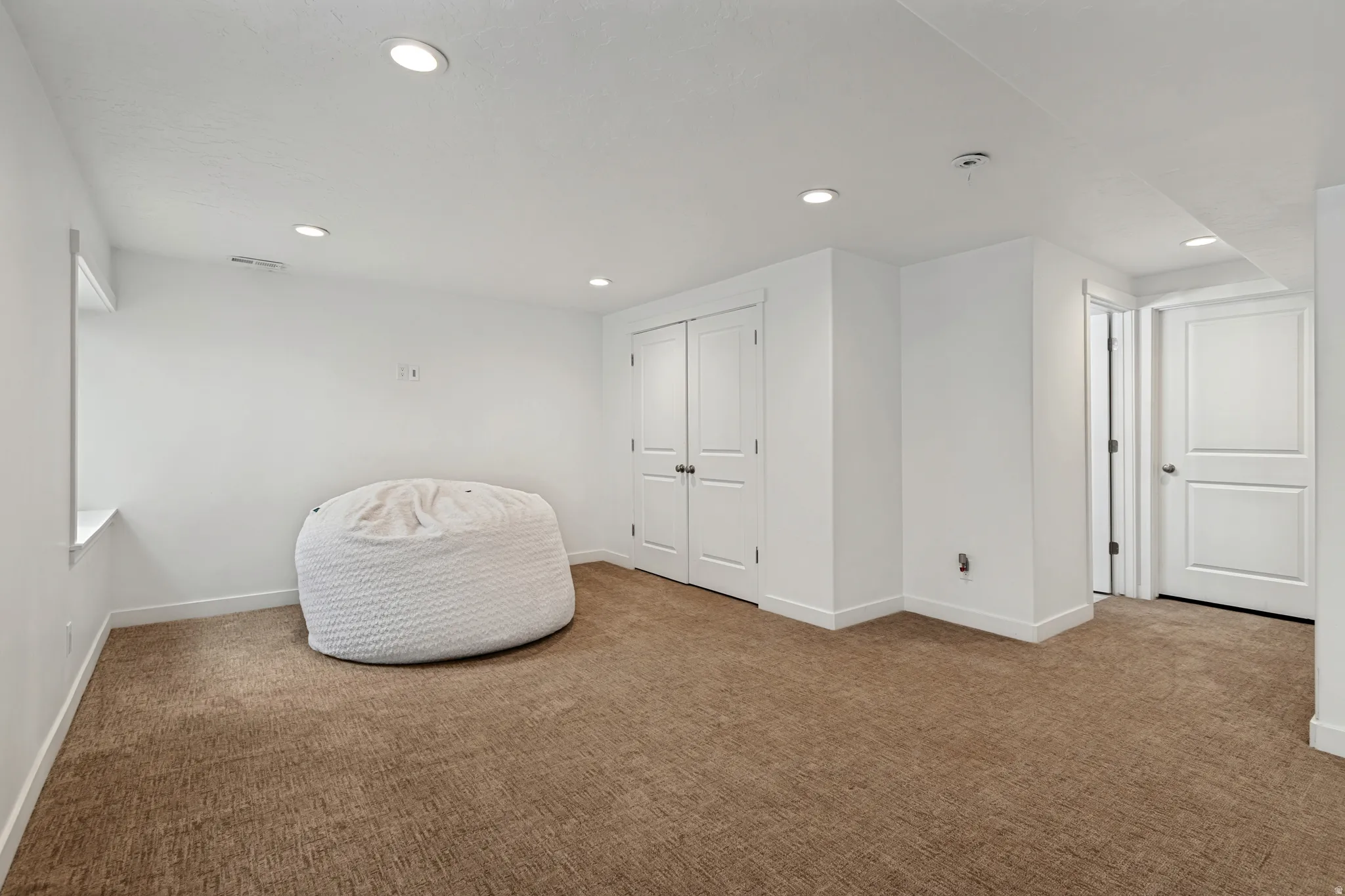 Spacious room featuring neutral carpet flooring, recessed lighting, and white trim