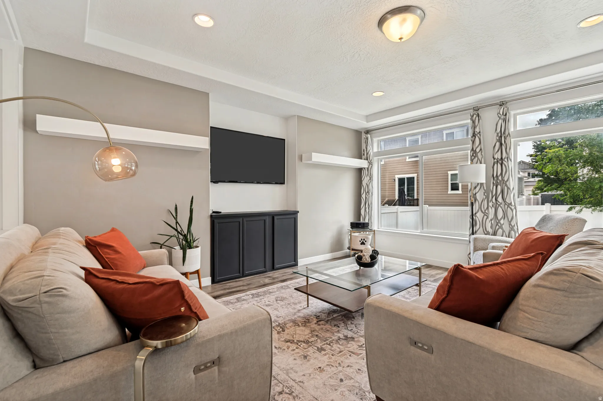 Living area featuring large picture windows, wood-finish flooring, a built-in media console, recessed lighting, and crown molding