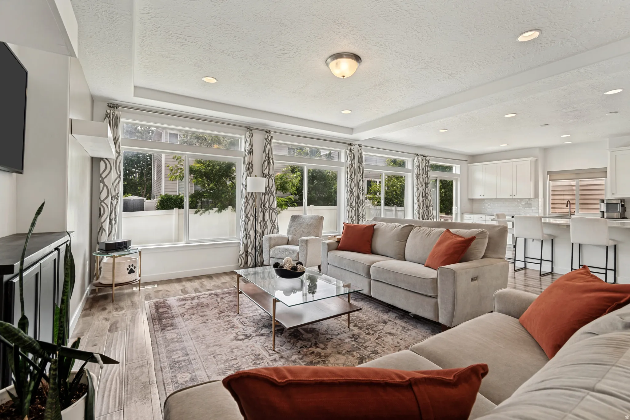 Open-concept living area featuring wood-finish flooring and ample natural light from multiple windows