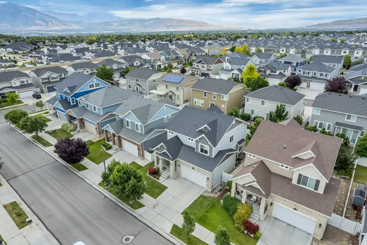 Residential street with a consistent architectural aesthetic featuring two-story homes with attached garages, manicured front lawns, and mature landscaping