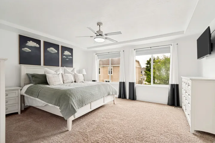 Spacious bedroom featuring neutral carpeting and a ceiling fan