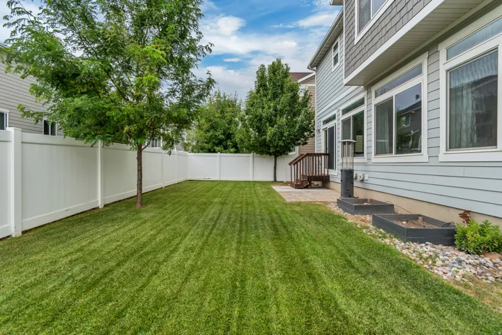 Expansive green lawn with a full white privacy fence