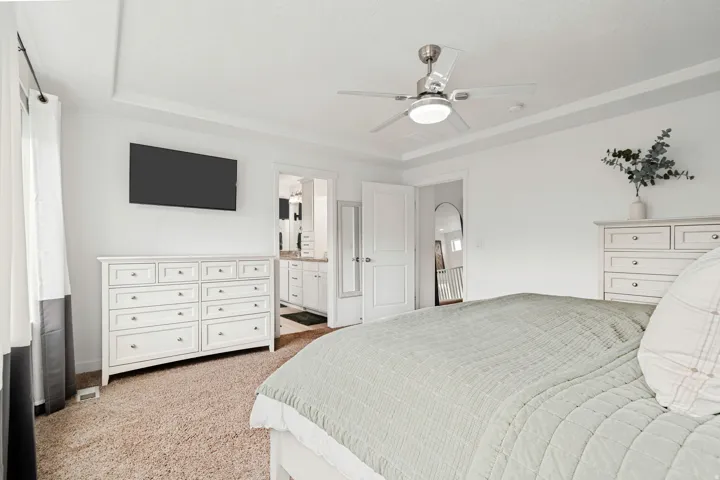 Carpeted interior room featuring a tray ceiling, recessed lighting, and a ceiling fan with integrated lighting