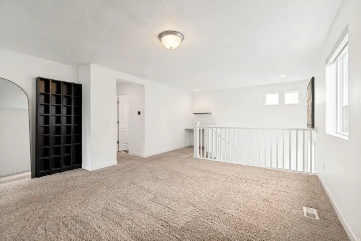 Spacious upper-level landing featuring neutral carpet, white walls, and a built-in shelving unit