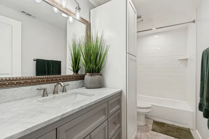 Bathroom featuring a vanity with a white stone countertop, undermount sink, and brushed nickel faucet