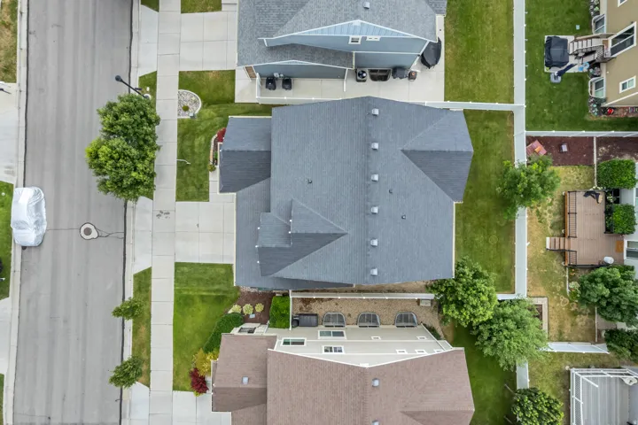 Aerial perspective showcasing a residential property with a dark shingle roof featuring multiple gables
