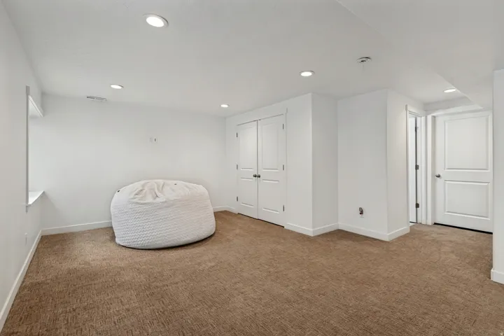 Spacious room featuring neutral carpet flooring, recessed lighting, and white trim