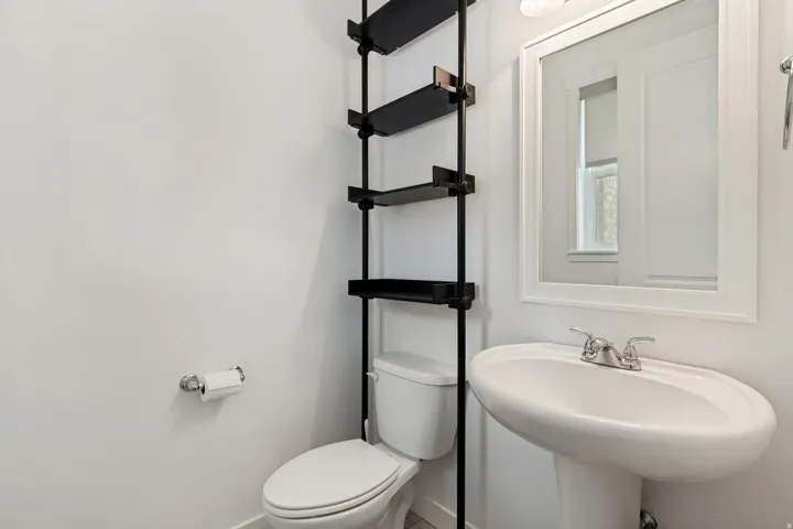 Pedestal sink with chrome faucet, framed mirror, and built-in shelving