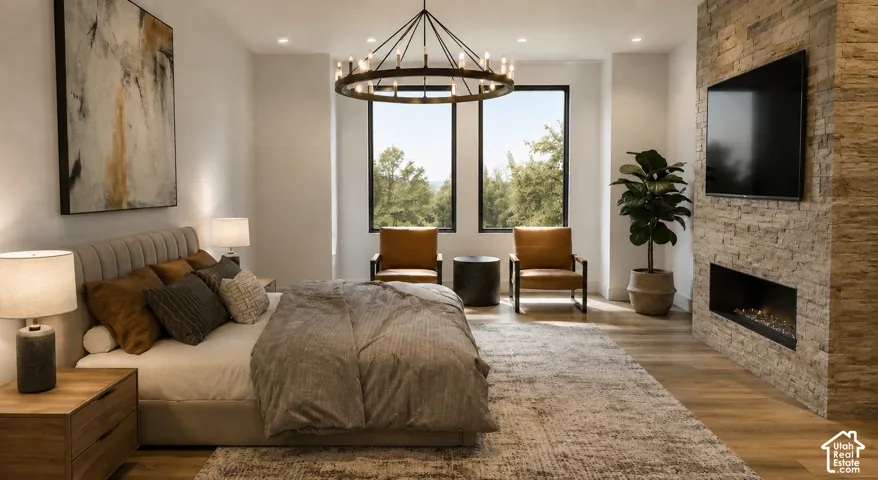 Spacious room featuring wood-finish flooring, a stone-clad fireplace with an integrated television, and two large windows with black frames