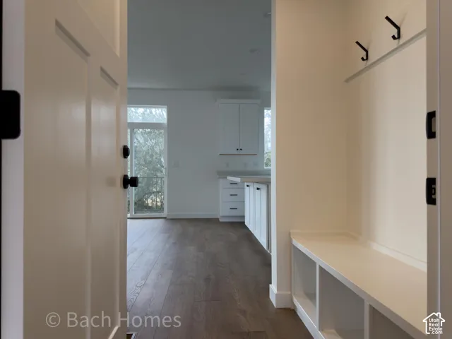 Entryway featuring wood-finish flooring, built-in storage bench with lower shelving, and wall-mounted hooks