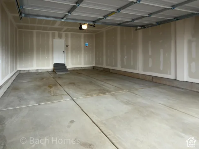 Multi-car garage featuring a concrete floor, finished drywall, an automated overhead door system, and a separate side entry door