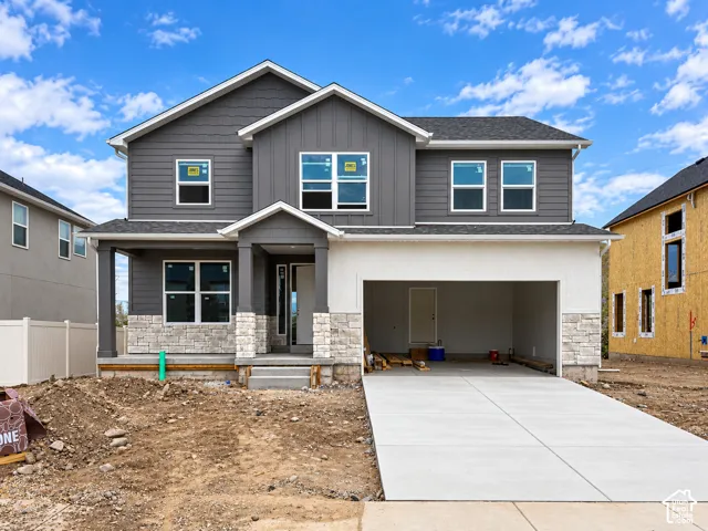Two-story residence featuring a gray horizontal siding and vertical siding facade, stone column accents, an attached two-car garage, and a covered porch entry